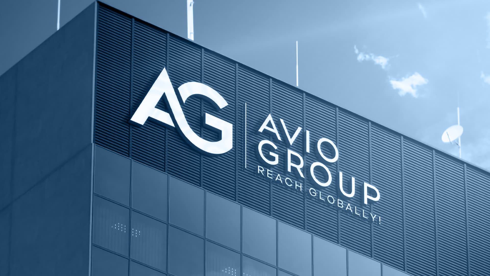 The Avio Group wordmark mounted on the facade of a modern building against a blue sky.